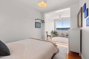 Ein Schlafzimmer mit Bett, Schreibtisch und Blick ins Freie.