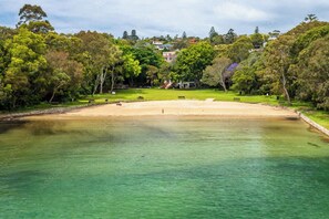 Ein Park mit sandigem Strand, klarem Wasser und umgebender Vegetation.