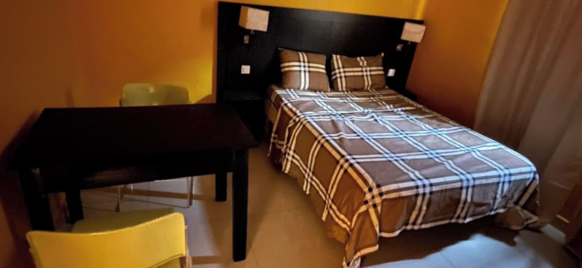 A small room with a bed, a table, and a chair.