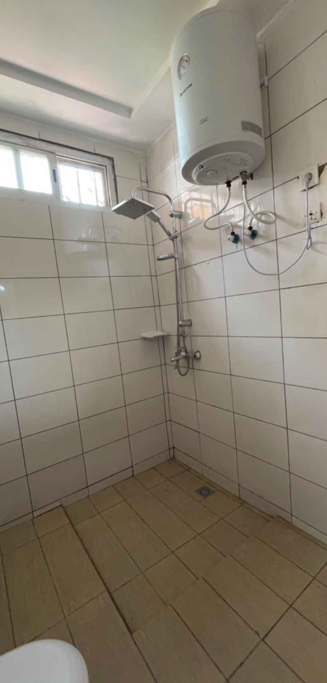 A bathroom with a shower, a toilet, and a water heater.