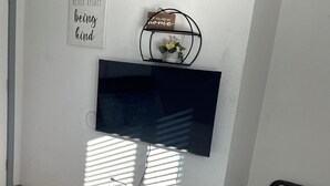 A wall-mounted TV with a flower vase and a motivational sign. - 11 - 1 king, 1 full, 1 queen, 2br, 1ba suite (Challenge-Brownsville)