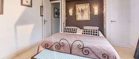 Ein Schlafzimmer mit Bett, Sitzbank, Tür und Wandleuchten.