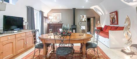 A dining area with a round table, chairs, and a TV on a cabinet.