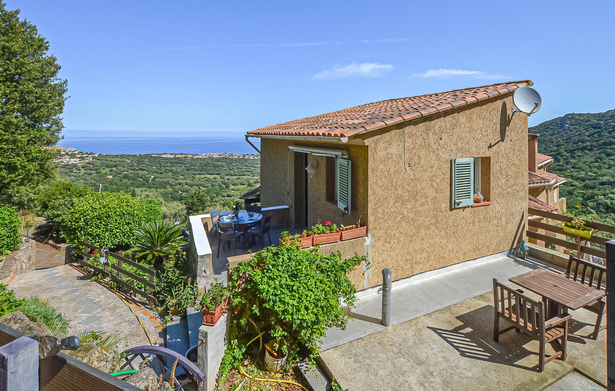 Ein kleines Haus mit einer Terrasse, Sitzgelegenheiten im Freien und Meerblick.
