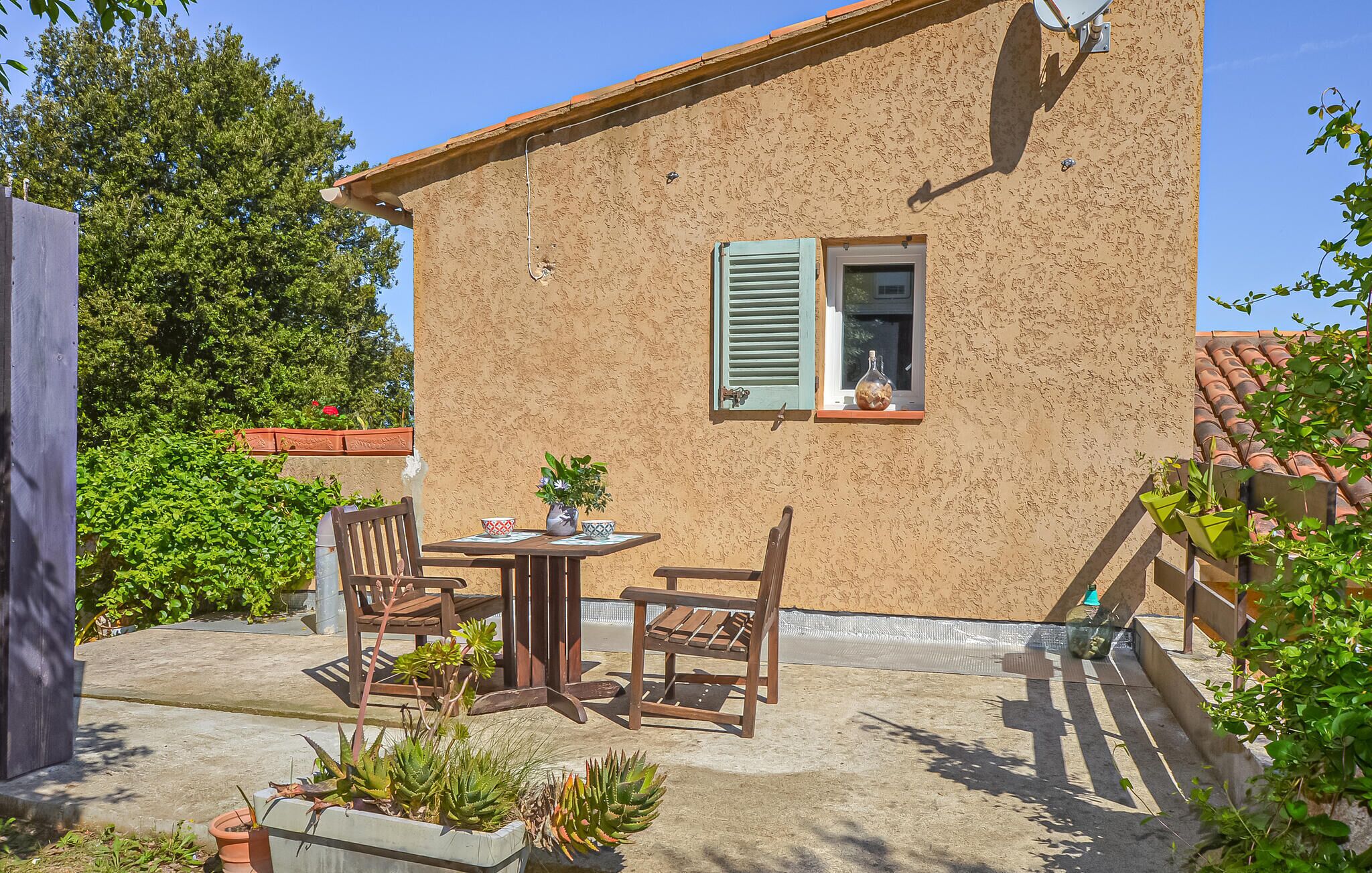A rustic building with a small patio, a table with chairs, and potted plants.