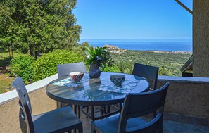 A table with chairs and a bowl, overlooking a coastal landscape. - PETITE MAISON VUE MER++ (MONTICELLO)