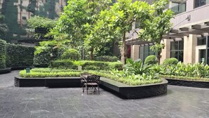 A courtyard with a seating area, surrounded by lush greenery and modern architecture. - STAYLUXIA Knightsbridge Delux 1BR, FREE Amenities, Pool, Netflix, Panoramic View (Makati)
