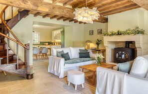 Ein Wohnzimmer mit Sofa, Hocker, Couchtisch aus Holz und Kamin.