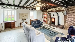 A living room with a fireplace, a sofa, a coffee table, and a window with a view of greenery. - Pet friendly home in Saint-Denis-le-Vêtu with WiFi (Saint-Denis-le-Vêtu)