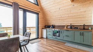 Une cuisine moderne avec des meubles en bois, un coin repas comprenant une table et des chaises, et une grande fenêtre offrant une vue dégagée.