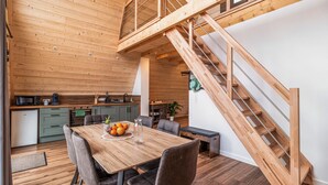 Une cuisine moderne avec des meubles en bois, un coin repas avec une table et des chaises en bois, et un escalier en bois.