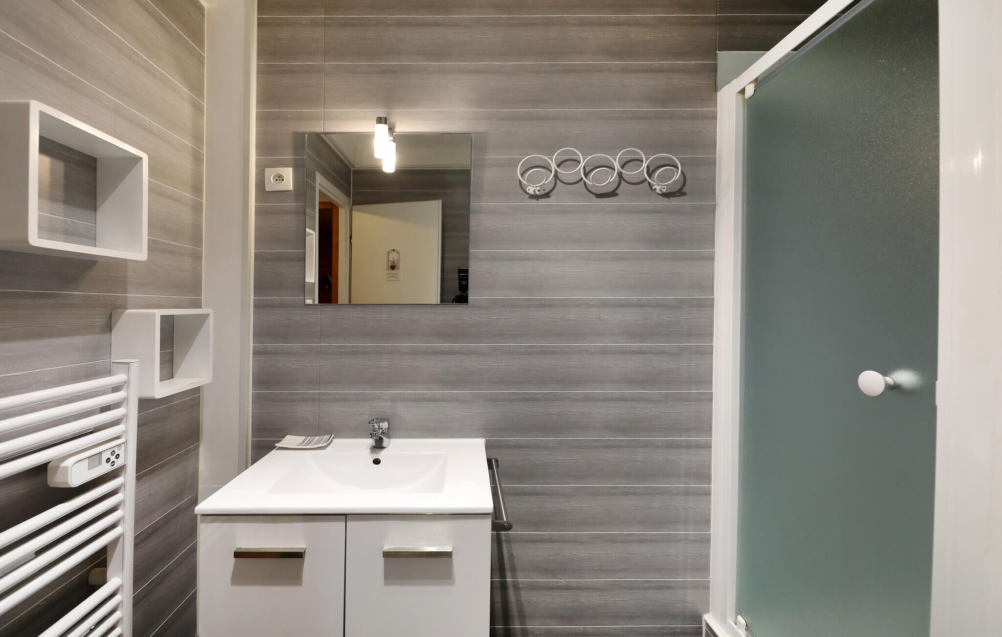 Une salle de bain moderne avec un lavabo blanc, un miroir et un porte-serviettes.