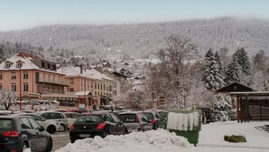 A snowy parking lot with cars and buildings in the background. - Amazing apartment in Gerardmer with lake view (Gerardmer)
