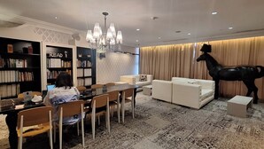 A modern living room with a dining area, a large bookshelf, a chandelier, and a unique black horse sculpture. - STAYLUXIA Knightsbridge Luxury 1BR with Balcony, FREE Pool, Netflix, Cityview (Makati)
