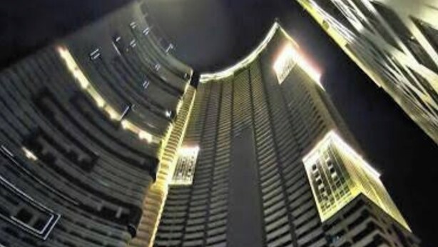 A high-rise building with a curved facade, multiple floors, and illuminated windows. - STAYLUXIA Knightsbridge Luxury 1BR with Balcony, FREE Pool, Netflix, Cityview (Makati)