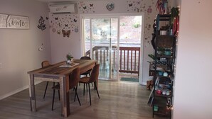 Zona pranzo con tavolo e sedie in legno, una libreria e una porta scorrevole in vetro che dà su un'area esterna.