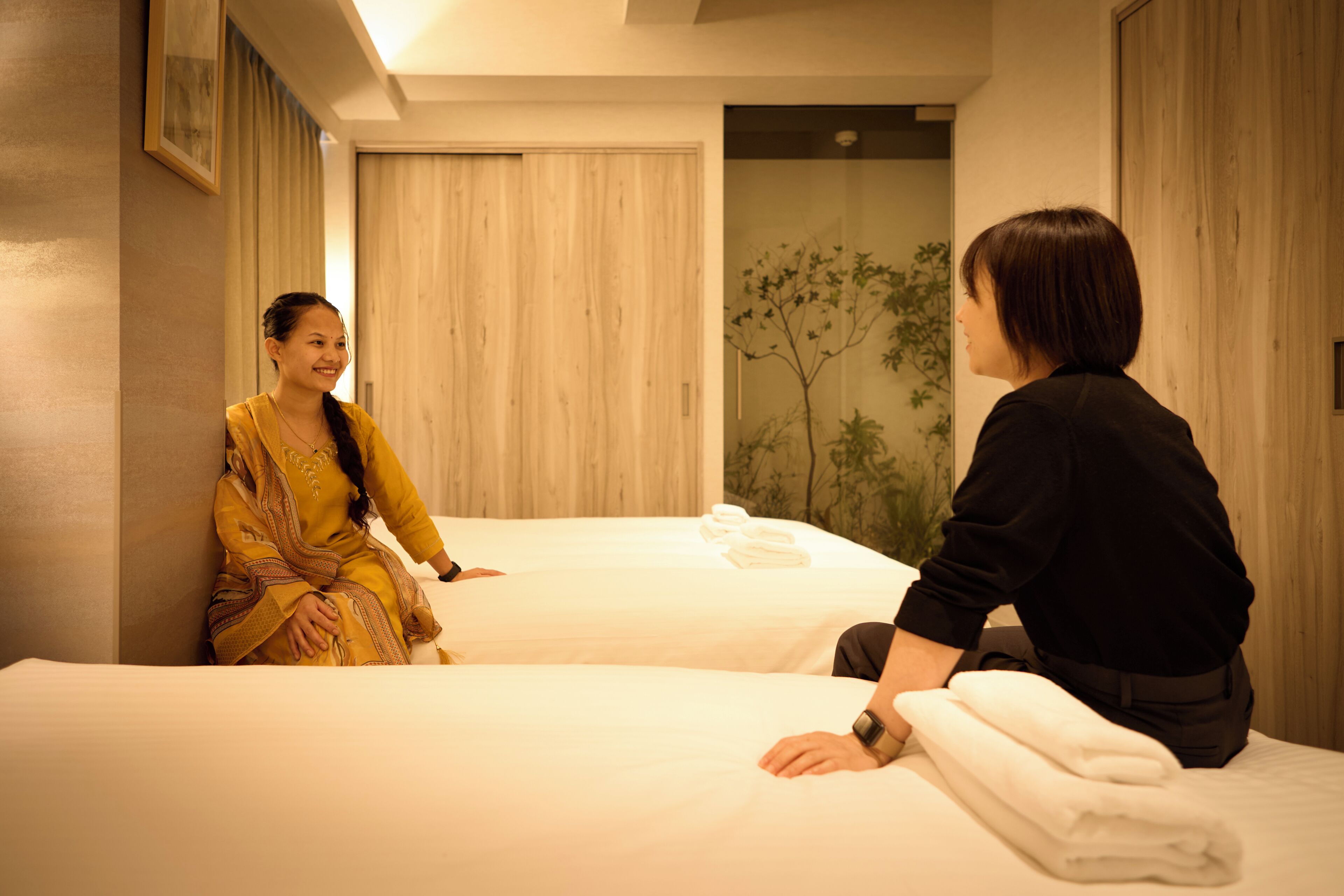 A hotel room with two beds, a wooden headboard, and a wall-mounted plant.