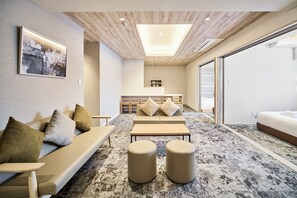 A modern interior with a sofa, ottomans, a dining area, and a bed. - WELLSTAY Namba Apartmenthotel-Cocochill (Osaka)