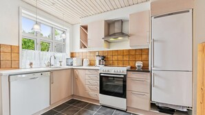 Eine moderne Küche mit weißen Schränken, einem Geschirrspüler von Bosch, einem Herd und einem Kühlschrank.