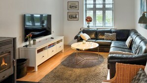 Ein modernes Wohnzimmer mit einer Ledersofa, einem Flachbildfernseher, einer weißen Unterhaltungsanlage, einem Kamin und einem großen Fenster mit Blick.