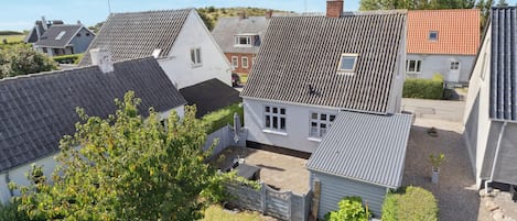 A residential area with houses featuring various roof styles and a small garden area with trees and a lawn.