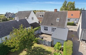 A residential area with houses featuring various roof styles and a small garden area with trees and a lawn.