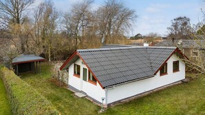 Ein eingeschossiges Haus mit Satteldach, einem kleinen Anbau und einem gepflegten Rasen.