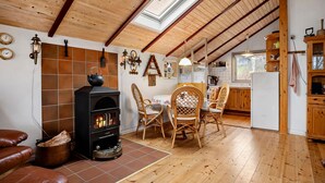 Eine gemütliche Küche mit Holzbalken, einem Kamin und einer Essecke mit Korbstühlen.