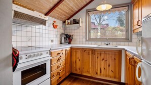 Eine Küche mit Holzschränken, einem weißen Herd und einem Fenster mit Blick auf Bäume und Gebäude.