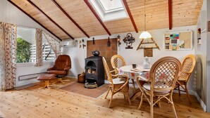 Ein gemütliches Zimmer mit Holzboden, Ledersessel, Tisch mit Stühlen, Kamin und Oberlicht.