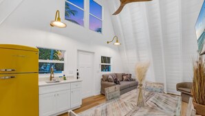 Una cocina moderna con armarios blancos, un refrigerador amarillo y un comedor con mesa y sillas de estilo rústico.