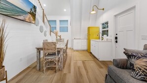 Una cocina moderna con armarios blancos, un refrigerador amarillo y un comedor con una mesa y sillas de madera.