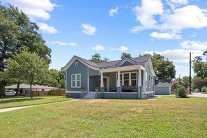 Ein bungalow mit Veranda, Garage und gepflegtem Rasen.