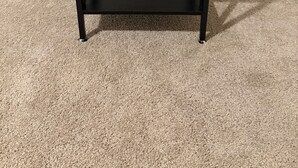 Un comodino nero con un cassetto e uno scaffale, posizionato su un tappeto color beige.