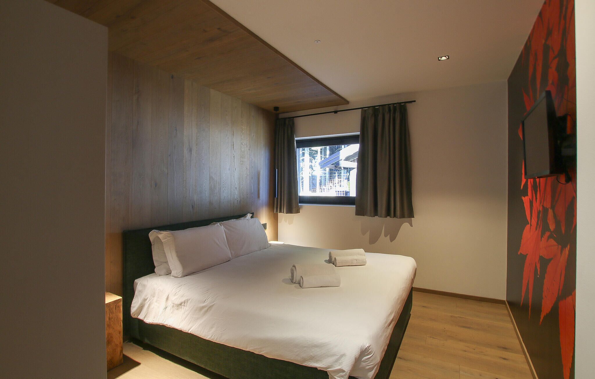 A hotel room with a bed, a window with curtains, and a painting on the wall.
