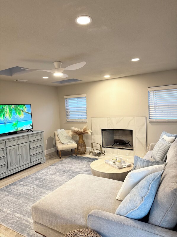 Una sala de estar moderna con chimenea, televisor y ventilador de techo.