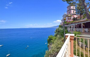 Vista costera con un edificio rosa que cuenta con balcones y un campanario.