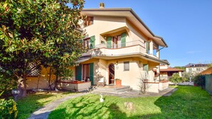 Ein zweistöckiges Haus mit Balkon, Veranda und kleinem Garten.