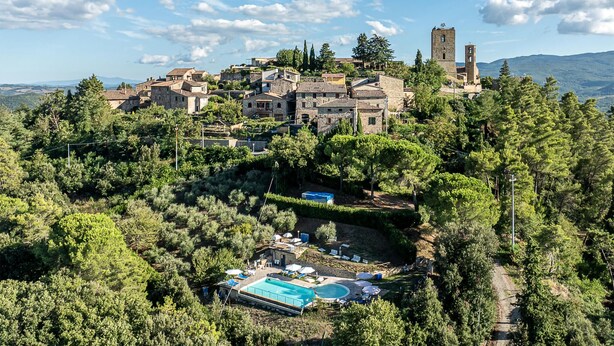A hillside villa with a swimming pool, surrounded by dense forest and featuring a prominent church tower. - Cozy apartment in Montecastelli Pisano (Montecastelli Pisano)