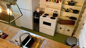 Una cocina compacta equipada con refrigerador, estufa, pileta y diversos utensilios.