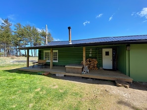 A log cabin with a porch, a chimney, and a stack of firewood.