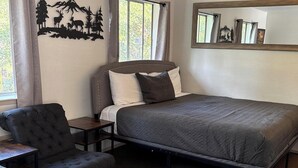 A neatly arranged bedroom with a bed, a chair, and a nightstand. - 21 - Great Suite for a great stay! (Challenge-Brownsville)