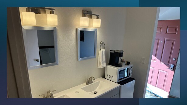 A modern bathroom with a white sink, two mirrors, a towel hanging, and a coffee maker. - 21 - Great Suite for a great stay! (Challenge-Brownsville)