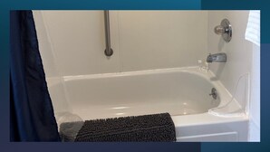 A white bathtub with a glass shower door, a towel rack, and a soap dispenser. - 21 - Great Suite for a great stay! (Challenge-Brownsville)