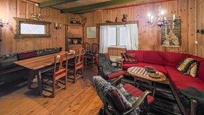 Ein gemütliches Blockhaus-Zimmer mit Holzwänden und Holzdielen, einem roten Sofa, einem Holztisch und einer Bank.
