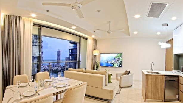 A modern living room with a dining area, a sofa set, a television, and a kitchen area with a dishwasher. - Twin Peaks Luxury 2-bedroom apartment with AC in tranquil Colombo (Colombo)