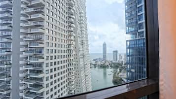 A high-rise building with multiple balconies and a view of a cityscape and water body.
