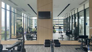 A modern gym with mirrored walls, large windows, and various exercise equipment.