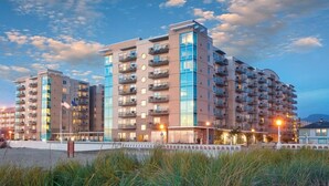 Un hôtel moderne à plusieurs étages, doté de balcons, situé près d’une plage.