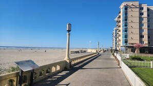 Une promenade en bord de mer avec une allée en béton, un lampadaire et un immeuble de grande hauteur en arrière-plan.